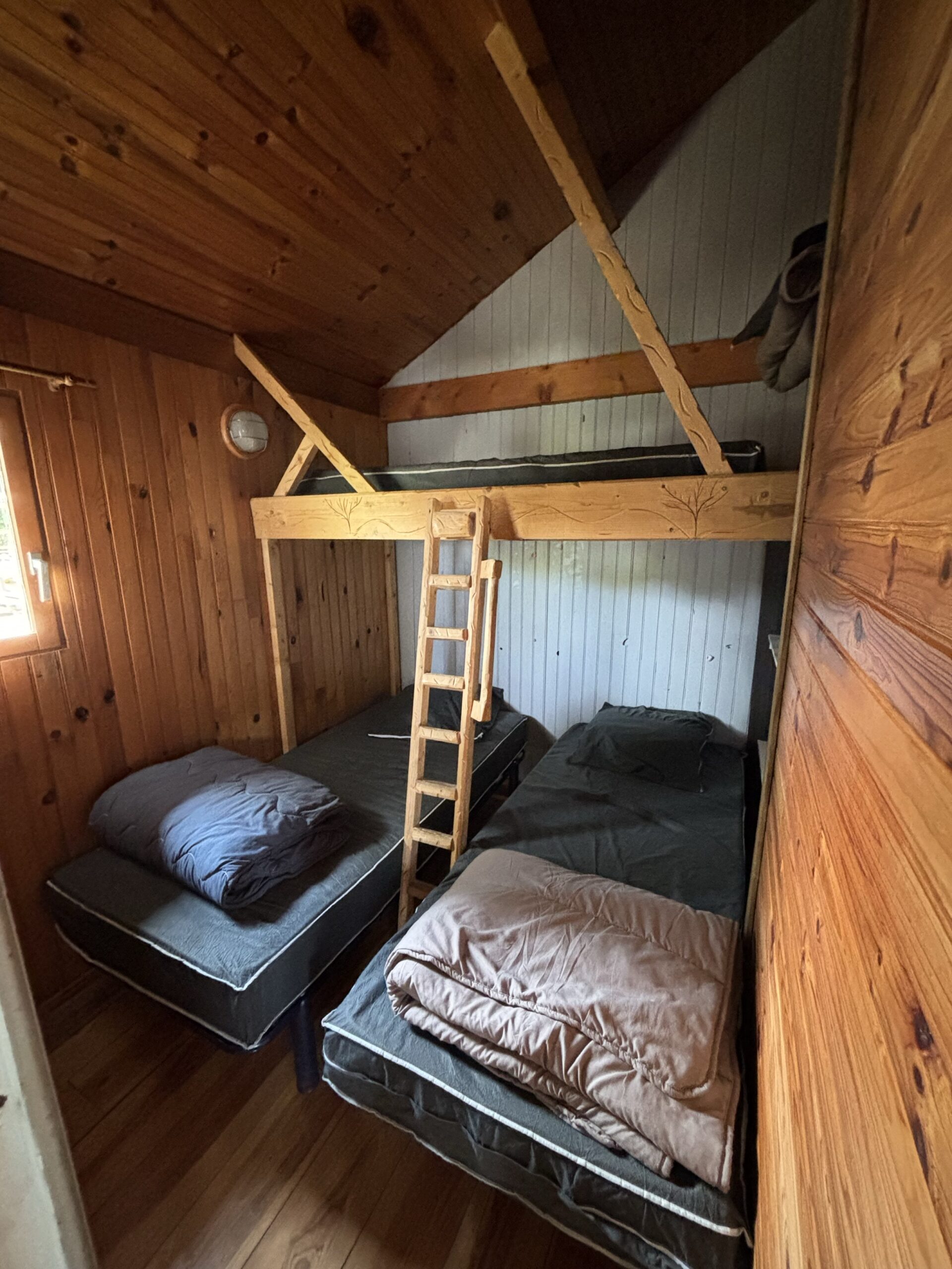 Deuxième chambre avec deux lits simples et un lit simple en hauteur dans le chalet des marrons