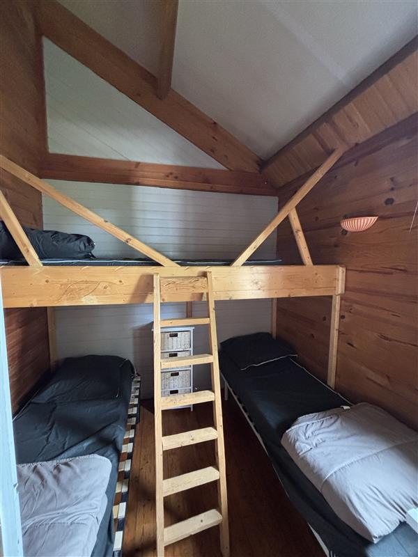 Chambre avec deux lits simples et un lit simple en hauteur dans le chalet des noix